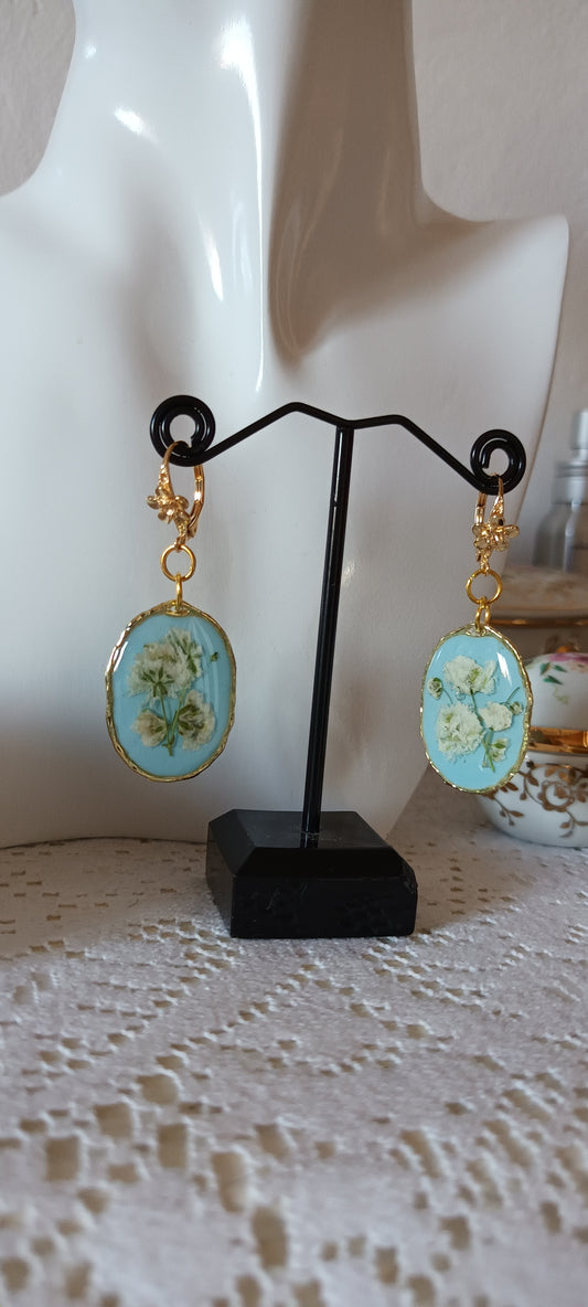 boucles d'oreilles en résine fleurs pressées blanches fond bleu ciel